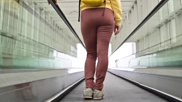 Kaukasische Frau steht auf einem Travolator. Das Mädchen erklimmt die Rolltreppe. — Stockvideo