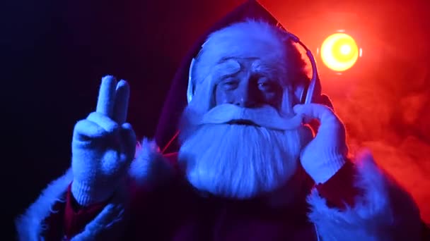 Ο Άγιος Βασίλης ακούει μουσική με ακουστικά σε ένα πάρτι. Μπλε κόκκινο νέον φως και καπνός. — Αρχείο Βίντεο