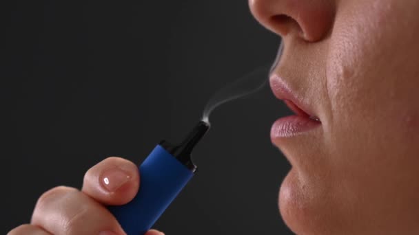 Donna caucasica fuma un vaporizzatore monouso in studio. — Video Stock