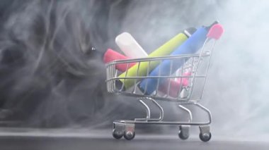 Siyah arka planda alışveriş arabasındaki tek kullanımlık buketler. Modern elektronik sigaralar.