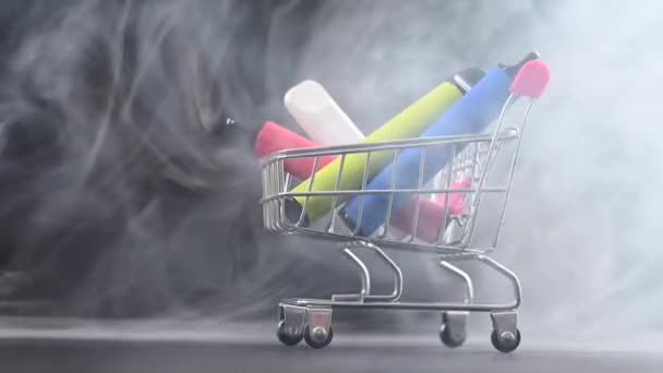 Einweg-Dämpfe in einem Einkaufswagen auf schwarzem Hintergrund. Moderne elektronische Zigaretten. — Stockvideo