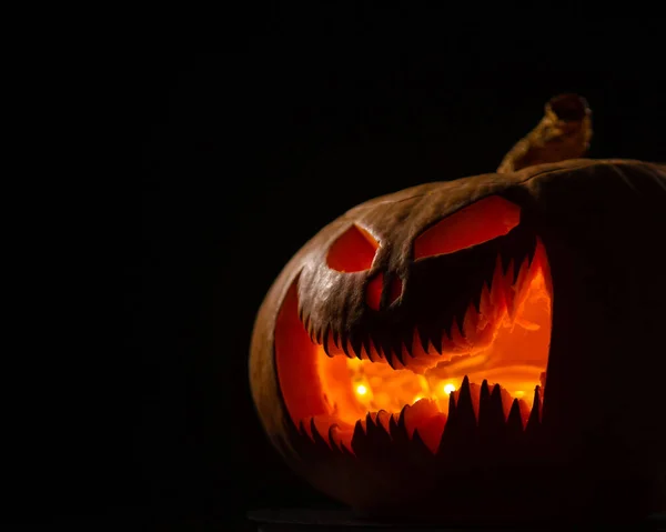 Una zucca raccapricciante con una smorfia scolpita brilla. Jack su una lanterna al buio. — Foto Stock