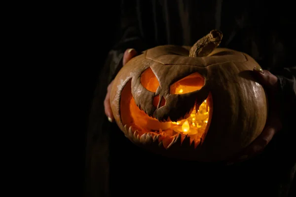 La bruja sostiene un gato de calabaza o linterna que brilla en la oscuridad. Halloween. —  Fotos de Stock