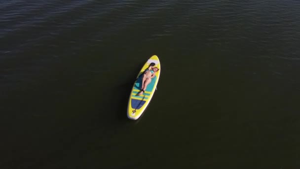 Mujer caucásica miente y se relaja en una tabla de sup. Vista superior. — Vídeos de Stock