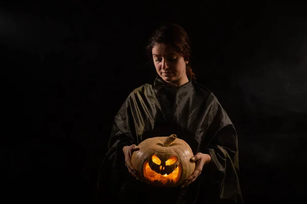 Mujer caucásica sosteniendo calabaza en la oscuridad — Foto de Stock