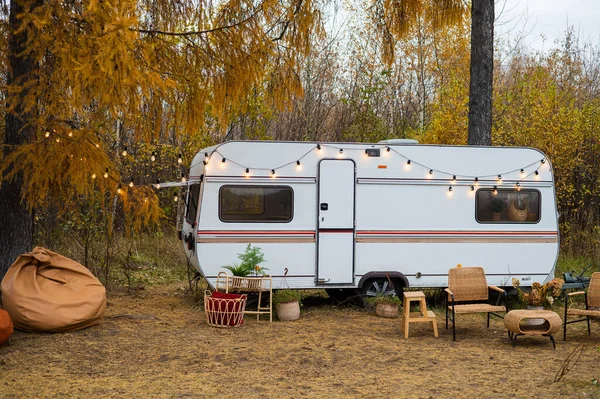 House on wheels. Cozy wicker furniture by the van against the backdrop of an autumn forest. — Stock Photo, Image