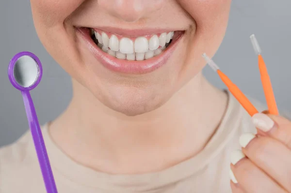 Retrato de cerca de una mujer sonriente sosteniendo un cepillo y un espejo dental. Pantalla panorámica —  Fotos de Stock