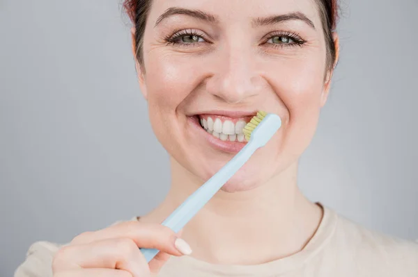 Retrato de perto da mulher caucasiana a escovar os dentes. A menina realiza o procedimento de higiene oral da manhã — Fotografia de Stock