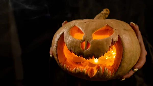 Die Hexe hält einen Kürbiskerl um eine Laterne, die im Dunkeln leuchtet. Halloween. — Stockfoto