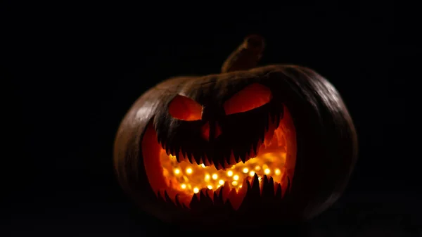 Een griezelige pompoen met een gesneden grimas gloeit. Jack op een lantaarn in het donker. — Stockfoto