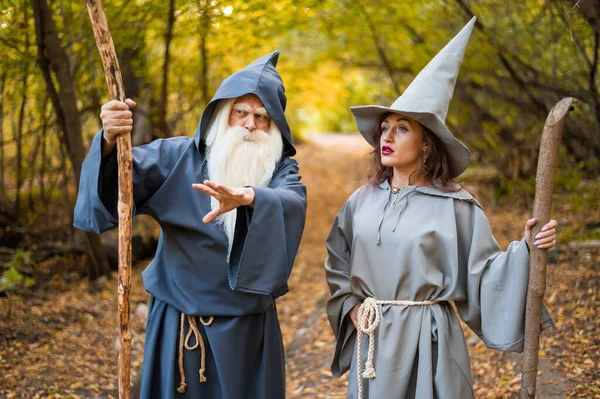 Mago y hechicera en el bosque otoñal. Anciano hombre y mujer en trajes de carnaval para Halloween — Foto de Stock