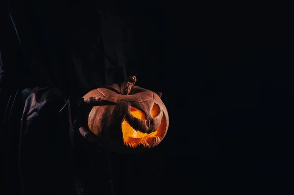 La strega sta tenendo una zucca jack o lanterna incandescente al buio. Halloween. — Foto Stock