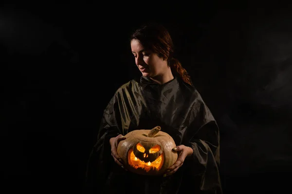 Mujer caucásica sosteniendo calabaza en la oscuridad — Foto de Stock
