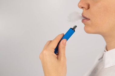 Beyaz arka planda tek kullanımlık sigara içen beyaz bir kadın. Sigara içmek için alternatif aygıt.