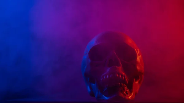 Menselijke schedel in roze en blauwe rook op een zwarte achtergrond. Halloween. — Stockfoto