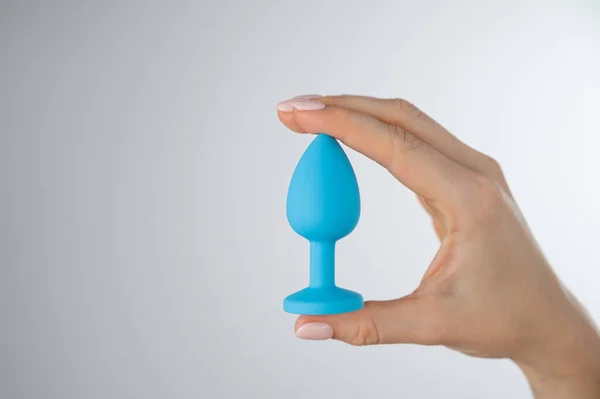 女人拿着蓝色的肛门插头在白色的背景上。供异性性爱的成人玩具 — 图库照片