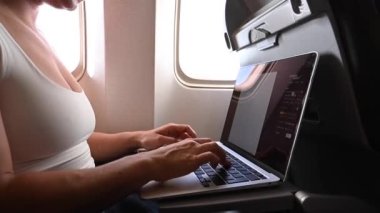 Maskeli meçhul kadın uçuş sırasında pencerenin yanında otururken dizüstü bilgisayarda çalışıyor. Serbest Çalışan Bir Yolculuk.