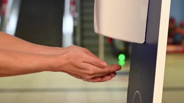 Een gezichtloze vrouw reinigt haar handen met een automatische desinfecterende dispenser op het vliegveld. — Stockvideo