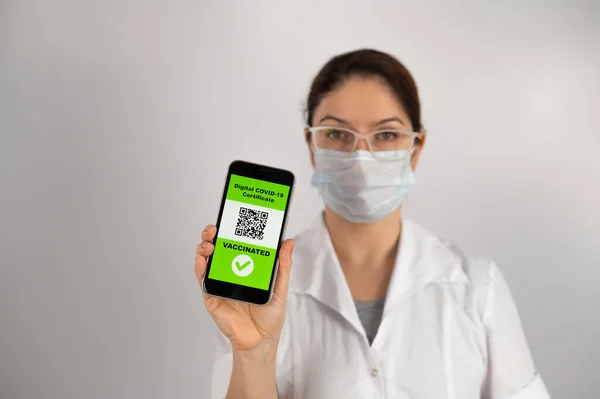 The doctor recommends vaccination and holds a smartphone with a QR code. — Stock Photo, Image