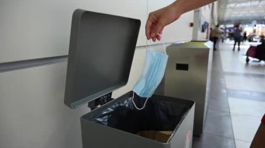 Kadın havaalanındaki çöp kutusuna maske atıyor..