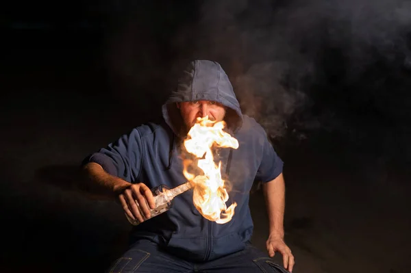 Muž v kapuci drží hořící láhev. Molotovův koktejl. — Stock fotografie