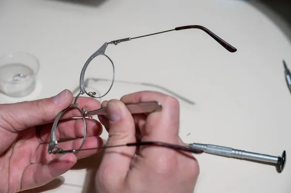 Montaż wkładek do nosa w okularach. Męski technik naprawia rozbite okulary. — Zdjęcie stockowe