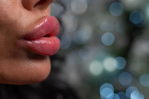 Zbliżenie dużych pulchnych żeńskich ust na tle świątecznych dekoracji. — Zdjęcie stockowe