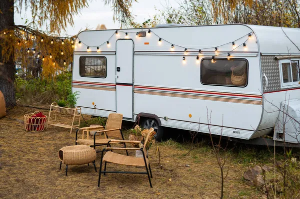 Camping-car ou mobil-home à la campagne. Confortable mobilier en osier par une remorque dans la forêt d'automne. — Photo