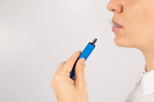 Mujer caucásica fuma vapor desechable sobre fondo blanco. Dispositivo alternativo para fumar. — Foto de Stock