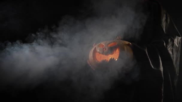 La strega sta tenendo una zucca jack o lanterna incandescente al buio. Halloween. — Video Stock