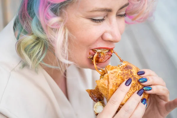 Běloška s kudrnatými vlasy, která jí hamburger. Špatné stravovací návyky a láska k fast foodům — Stock fotografie