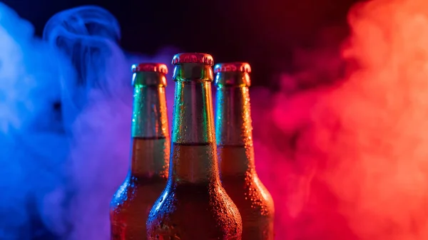 Три бутылки пива в сине-розовом тумане. — стоковое фото