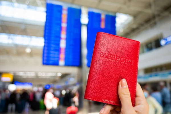Havaalanı bilgi panosunun arka planında pasaportu olan bir kadın..