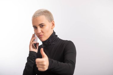 Kısa saçlı beyaz bir kadın beyaz arka planda akıllı telefon kullanıyor..