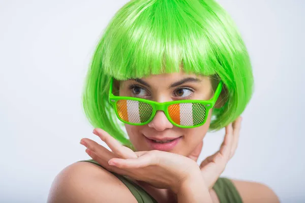 Cheerful young woman in green wig and funny glasses celebrating st patricks day on a white background — Stock Photo, Image