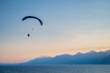 Gün batımında denizin üzerinde uçan bir adamın silüeti..