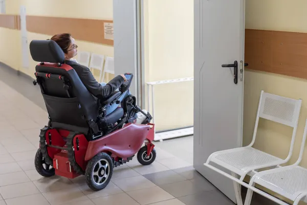 Caucasian woman in electric wheelchair in university corridor.