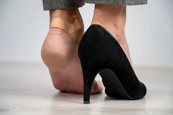 Een vrouw in zwarte schoenen doet een pleister op een maïs — Stockfoto