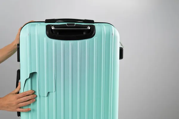 Женщина демонстрирует сломанный чемодан на белом фоне. Поврежденный багаж во время полета. — стоковое фото