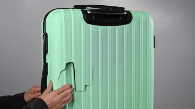 Bir kadın beyaz arka planda kırık bir bavulu gösteriyor. Uçuş sırasında hasarlı bagaj..