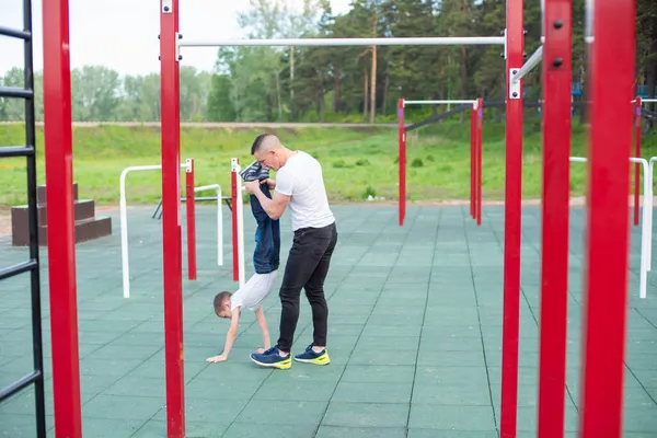 Uomo caucasico insegnamento figlio manubrio al parco giochi. — Foto Stock