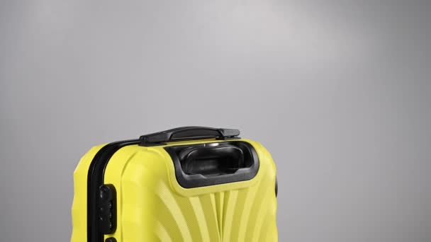 Желтый чемодан вращается на белом фоне. — стоковое видео