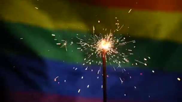 Sparklers met golvende lgbt regenboog vlag achtergrond. — Stockvideo