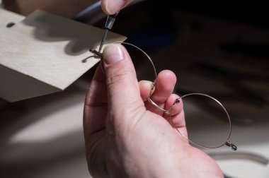 Optik teknisyen gözlükleri tamir ediyor. Tornavida ve gözlük çerçeveli erkek ellerinin yakın çekimi.