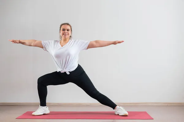 Mladá tlustá žena dělá flexibilní cvičení na bílém pozadí — Stock fotografie