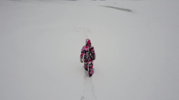 Mujer caucásica camina en overoles de invierno en la nieve. Vista del dron. — Vídeos de Stock