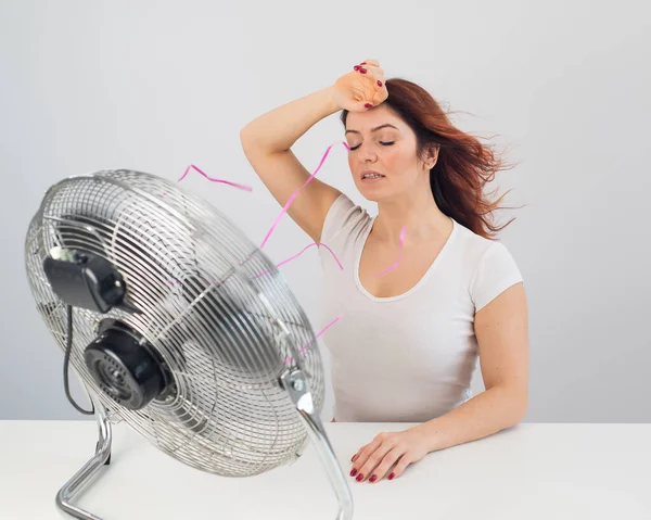 Radostné běloška žena těší vítr fouká z elektrického ventilátoru na bílém pozadí. — Stock fotografie