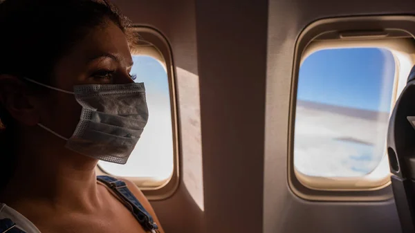 Mujer caucásica usando una máscara médica a bordo del avión. — Foto de Stock