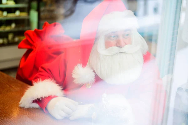 O Pai Natal está sentado num café. Vista exterior através da janela. — Fotografia de Stock