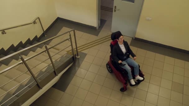 Кавказька жінка в електричному кріслі гусениці піднімається сходами.. — стокове відео